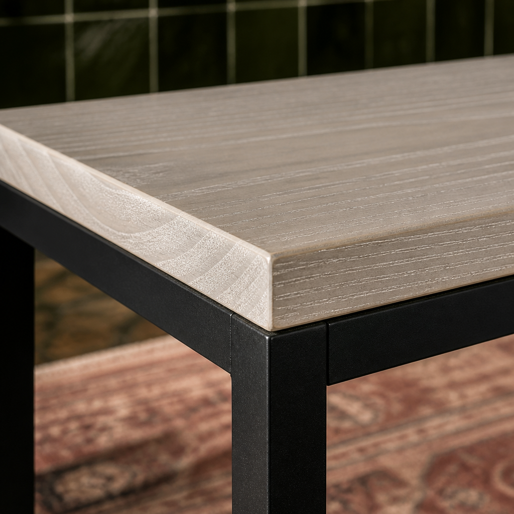 Close view of the limed ash grey top edge and chamfer meeting the matte black steel leg