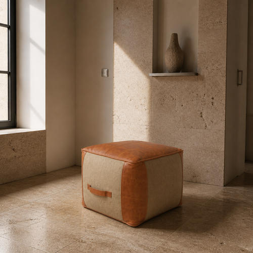 Jute and tan faux leather square pouf in a travertine gallery interior beside a deep window reveal