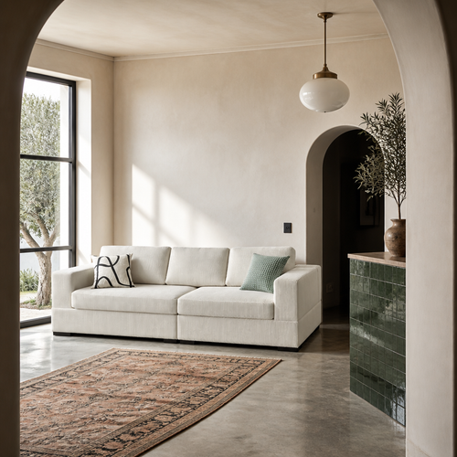 Ivory corduroy sofa in a Mediterranean room with lime plaster walls and a concrete floor