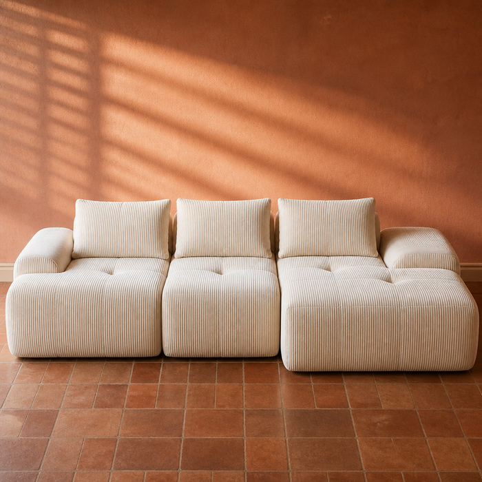 Cream wide-wale corduroy modular boneless sofa, close portrait against a rust clay plaster wall on terracotta tile