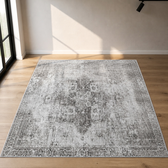Grey distressed low pile area rug, close hero view on a white oak floor