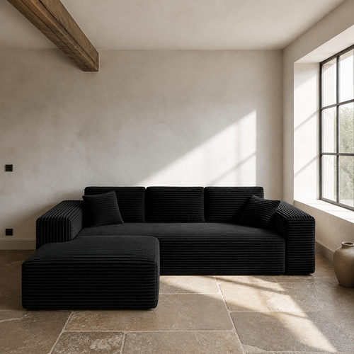 Black corduroy chaise sectional in a chalk white lime wash room with a limestone flag floor