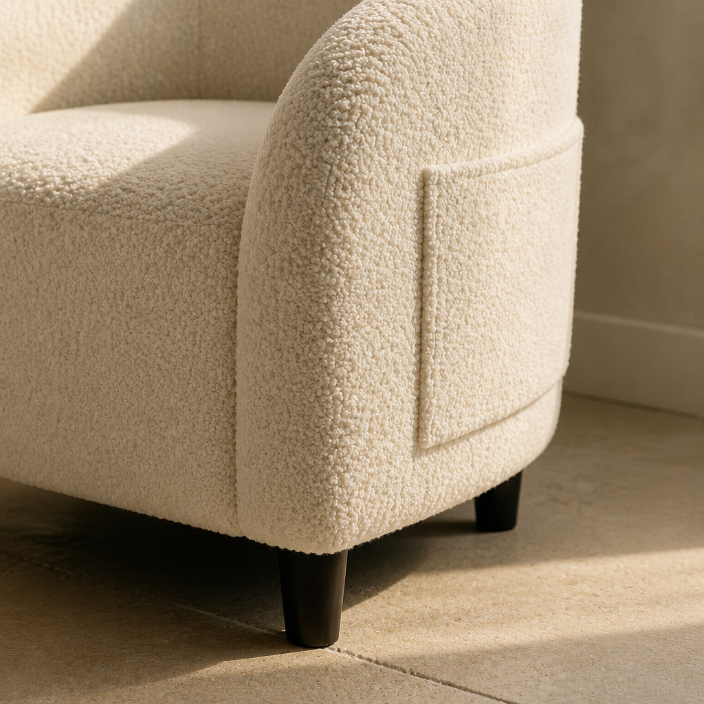 Close detail of the cream boucle pile and tapered espresso leg of the accent chair