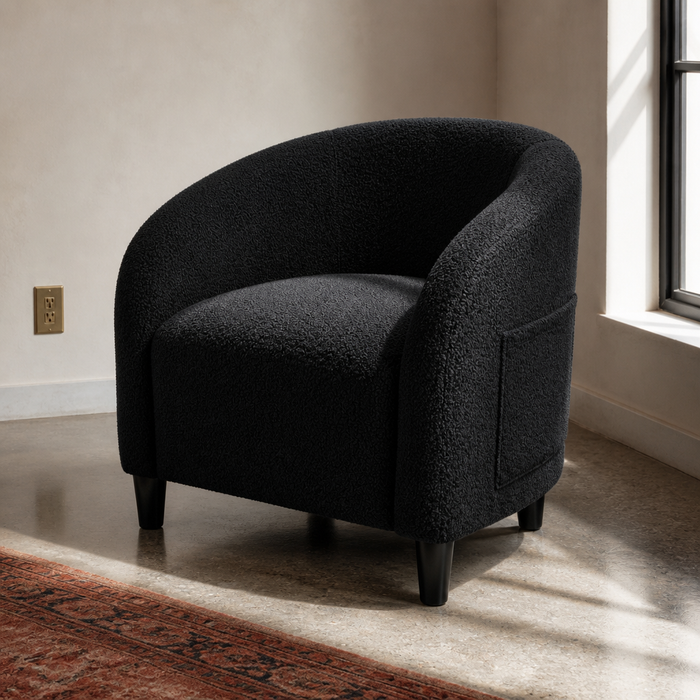 Black boucle barrel accent chair, close front three-quarter portrait in a bone plaster room