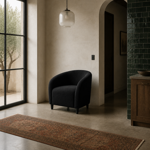 Black boucle barrel accent chair in a mediterranean room with zellige tile and terracotta runner