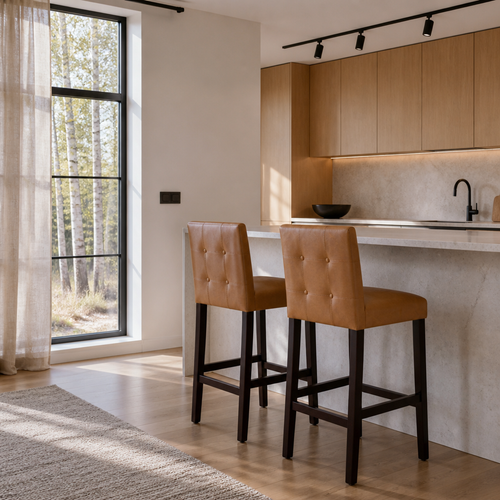 A pair of tan vegan leather bar stools at a stone counter in a white oak kitchen