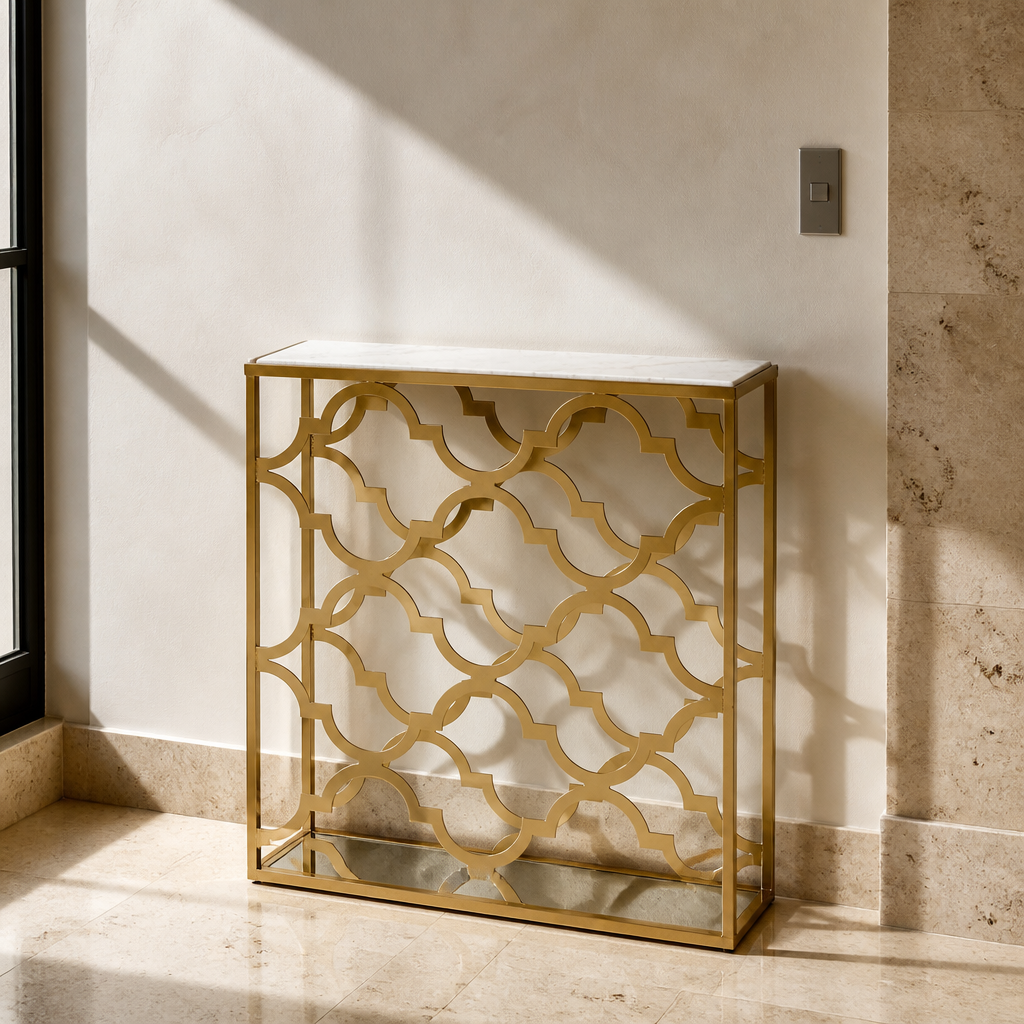 Narrow gold quatrefoil console table with white marble top, close portrait against travertine