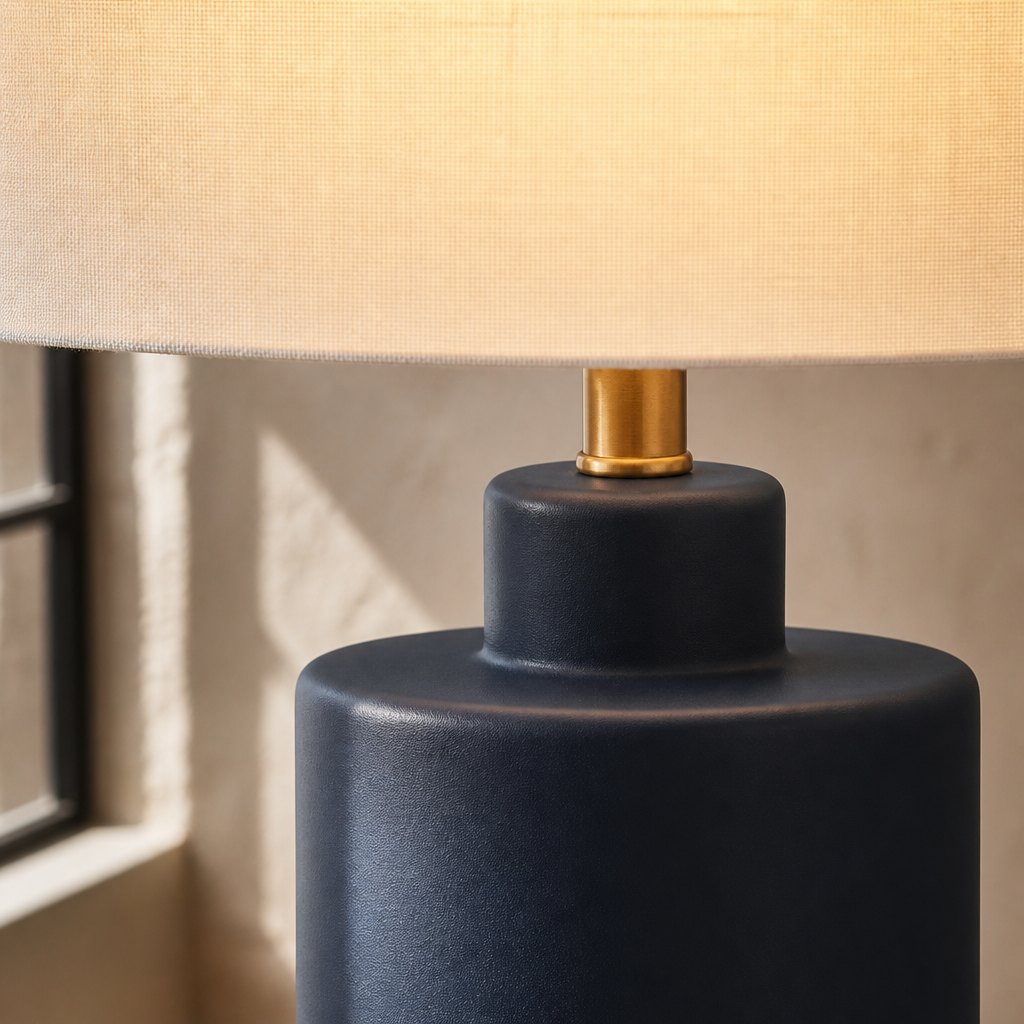 Close detail of the navy ceramic collar meeting the antique brass neck on the Carlina table lamp