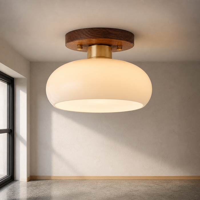 Walnut toned semi flush ceiling light with an opal glass shade and brass collar, close view against lime plaster