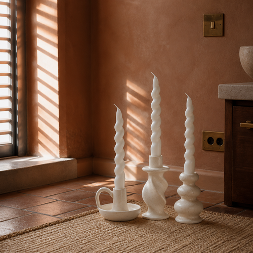 Set of three ceramic candle holders styled on terracotta tile in a rust plaster room