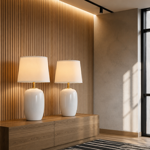 Two white ceramic table lamps lit on a console against a backlit oak slat wall