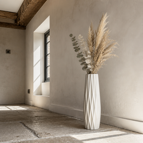Faceted white ceramic floor vase on limestone flags against a chalk lime wash wall