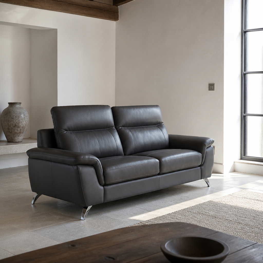 Chicago charcoal leather sofa styled beneath a timber beam in cool north light with one hard sun patch on the stone