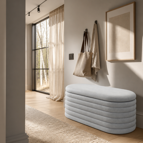 The light grey oval chenille storage bench along an entry hall wall in a Nordic oak interior with a white oak plank floor
