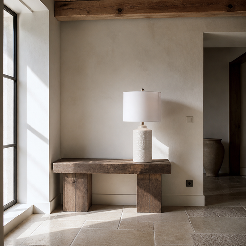 Embossed white ceramic table lamp in a chalk white lime wash room with limestone flags