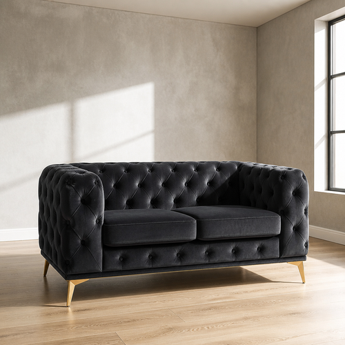 Black velvet Chesterfield loveseat with deep diamond button tufting and brass legs, 61.25 inches wide, against a microcement wall