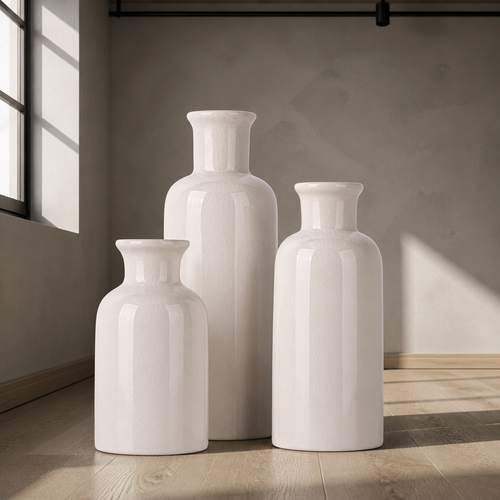 Set of three glossy white ceramic bottle vases in graduated heights against warm grey microcement
