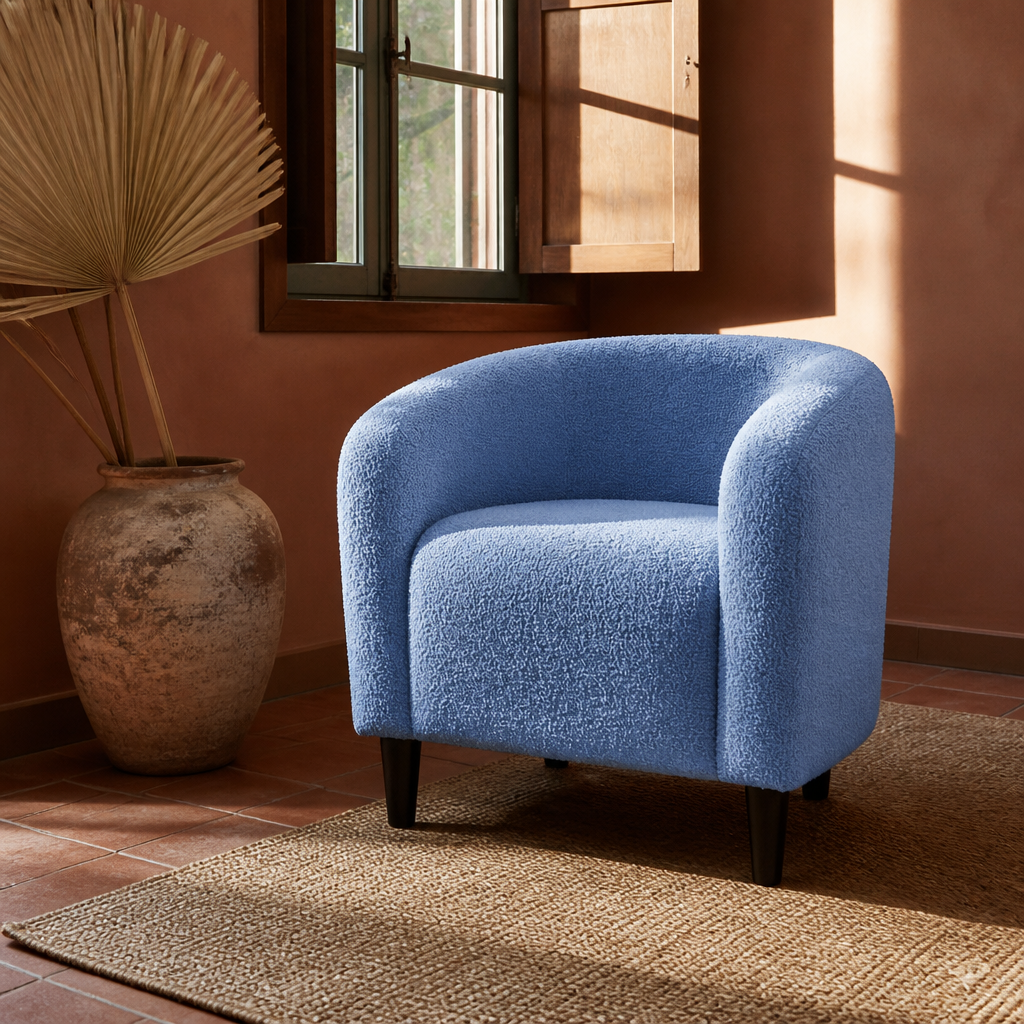 Blue boucle accent chair on a jute rug beside a dried palm in a clay vessel