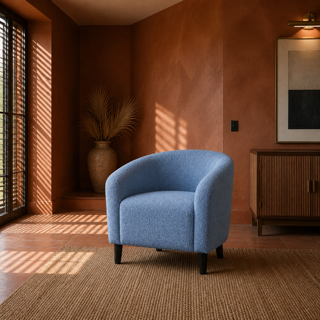 Blue boucle accent chair in a wide terracotta tiled room with louvre shadows