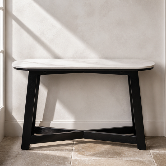 White marble console table with black splayed wood base, front view
