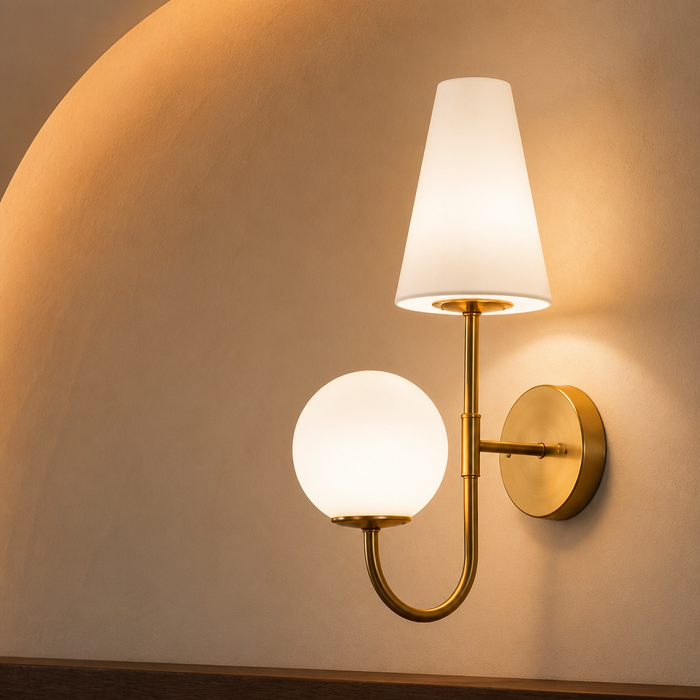 Brass wall sconce with a white glass cone shade and opal globe on curved plaster