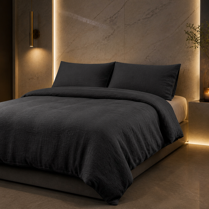 Farmhouse Linen Duvet Set in dark grey stonewashed linen with two matching pillowcases, made up on a bed in a warm marble bedroom