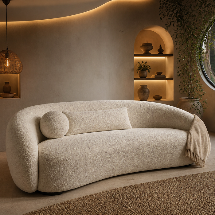Juliet Sofa, curved ivory boucle three seater against a curved plaster wall